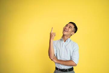 excited asian young man with fingers pointing up on isolated background