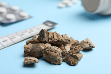 Pile of kidney stones on light blue background, closeup
