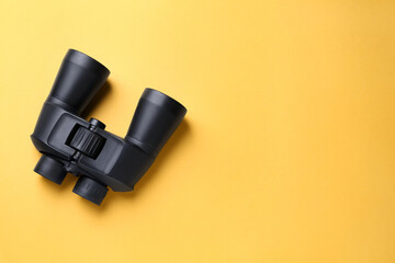 Modern binoculars on orange background, top view. Space for text