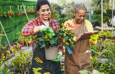 Multiracial women working inside greenhouse garden - Focus on african female face