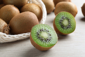 Cut and whole fresh kiwis on white wooden table, closeup
