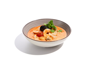 Traditional asian soup - tom yam with prawn and coconut milk isolated on white background. Tom yam kung with seafood and coriander in gray bowl on white background.