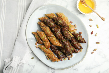 Delicious baklava with pistachio nuts and honey on white marble table, flat lay