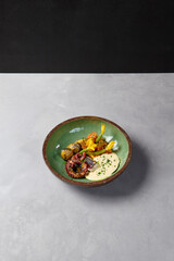 Grilled octopus with baby potatoes and tomato salad. Innovative recipes in handmade ceramic dishware. Cooked octopus in modern style