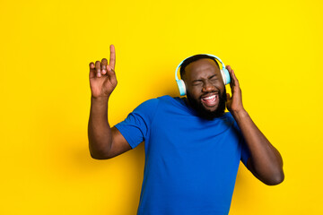 Portrait of attractive cheerful guy listening best chart hit having fun isolated over bright yellow...