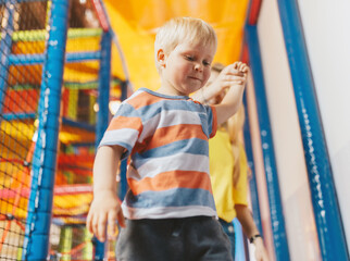 Happy boy having fun in amusement entertainment park with nanny. Schhol kids playing in kindergarten. Boy holding teacher nanny hand