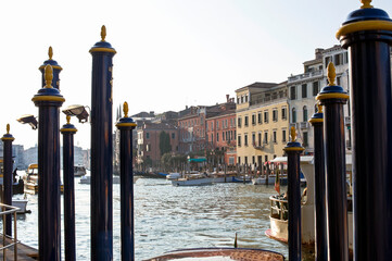Canal Grande moorings with gondolas and boats in navigation at sunset.