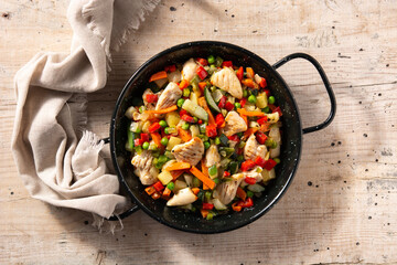 Chicken stir fry and vegetables on wooden table	