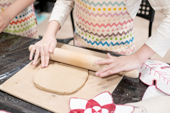 child potter rolls a brown clay with rolling pin on a special board on a wooden table to make a plate.Pottery workshop.Pottery workshop. teaching schoolchildren. hobbies and leisure for children. - Powered by Adobe