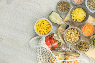 Various vegan organic products in glass jars and bowls on a white wooden background. Zero waste shopping and storage farm products. Top view, copy space.