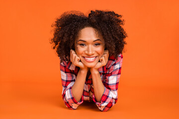 Photo of pretty adorable woman wear plaid shirt having rest arms cheeks isolated orange color background