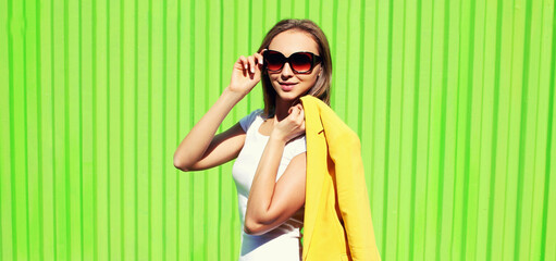 Portrait of beautiful young woman wearing yellow suit with posing on vivid green background, street fashion
