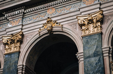 Arch and pilasters with gold Corinthian capitals inside the Jesuit Cathedral in Lviv, Ukraine. Medieval interior design concept. - obrazy, fototapety, plakaty