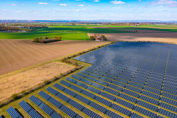 Aerial view of a solar park with many photovoltaic panels next to agricultural fields in rural...