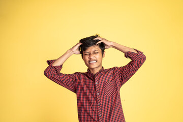 Stressed asian young businessman holding his head over isolated background