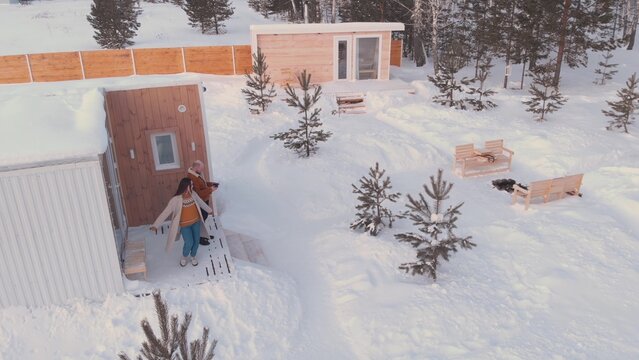 A Husband And Wife Are Resting In A Country House For The Winter Holidays, Celebrating New Year's Holidays Together In A Quiet Place On The Edge Of The Forest In Their Small House. Drone Video.