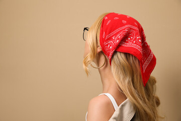 Young woman with stylish bandana on beige background. Space for text - obrazy, fototapety, plakaty