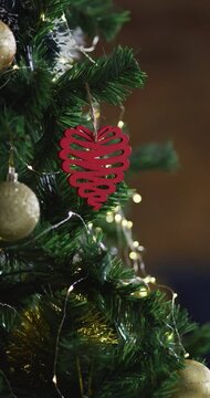 Vertical close-up shot of a red heart-shaped Christmas ornament on a tree