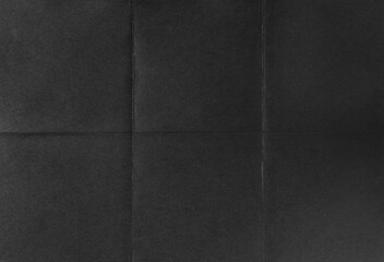 Black crumpled unfolded paper sheet texture background. Paper folded in six. Full frame