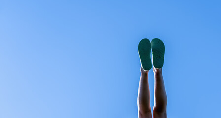 Feet of carefree happy young child girl against blue sky. Summer holiday and happy childhood concept. Copy space. Horizontal image.