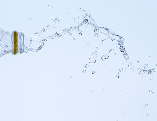 Splash of water from a bottle on a white background. Reflection on the surface of the water.
