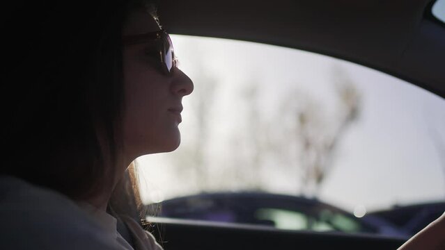 Confident woman drives car in a traffic jam. Businesswoman in sunglasses holds on to the wheel of a car 4K 10 BIT