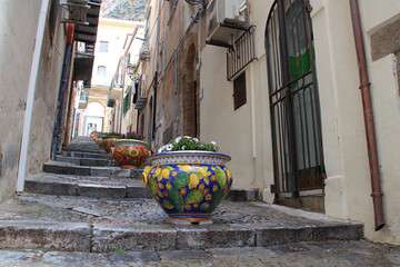 jars in an alley with steps in cefalù in sicily in italy 