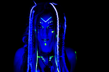 portrait of a girl in blue light with glowing neon braids and makeup in the dark