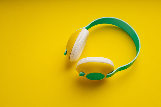 Colourful wireless headphones on yellow background