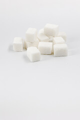 Fototapeta na wymiar Heap of sugar cubes on white background, place for text