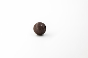 One round brown chocolate candy with a pattern like a globe of the earth on a white background