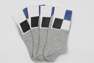 stack of new gray socks with blank labels on white background, close-up top view