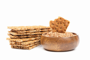 Stack of buckwheat crispbread and grain in a wooden bowl isolated on white background. Healthy snack