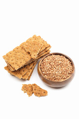 Stack of buckwheat crispbread and grain in a wooden bowl isolated on white background. Healthy snack