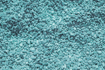 a lot of even identical colored light blue rounded pebbles, sunny beach, top view, pattern background