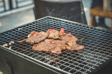 Multiple slices of premium meat are grilling on the stovetop. Close up of grilling meat on the charcoal grill. Sliced beef on charcoal grill at Outdoor party. Home made barbecue beef grill smoke.