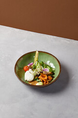 Salad bowl with salmon, avocado, broccoli, vegetables and egg on homemade ceramic plate. Buddha bowl with salmon, broccoli, quinoa in modern serveware. Modern ceramic dishware on concrete background.