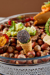 Appetizers set on luxury plate with hazelnut. Creative platter of appetizers from inspirational chef. Salmon cheesecake, fish tartar, pastrami crocket, liver pate, baked mini-paprika