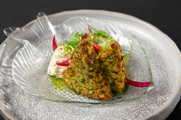 Zucchini fritters with fish ceviche and cheese cream. Healthy food - vegetables fritters and fish tartar. Inspirational chefs food on dark background. Modern food. Contemporary menu for restaurant.