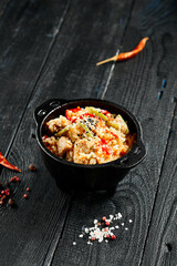 Chicken fried rice on wok. Asian food - fried rice with vegetables, egg and chicken on dark table. Wok menu on black wood background. Traditional chinese food.