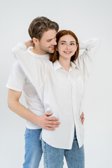 Smiling man hugging redhead girlfriend isolated on white.