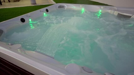 Close-up of the surface of a modern hot tub for relaxation therapy and rehabilitation in a hotel. Bubbles of water in a bath under oxygen pressure In evening outside with lights