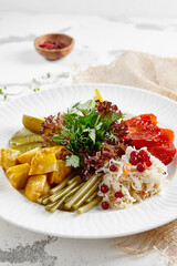 Appetizers from pickled vegetables in white stone background. Authentic food in restaurant menu. Mix from salted tomatoes, cucumber,  pickled pepper, sauerkraut. Assorted from marinated vegetables.