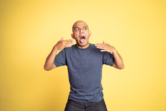 bald young man opening his mouth with spiciness expression on isolated background