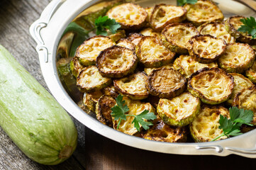 Fried zucchini with parsley in plate on rustic background, vegetarian food