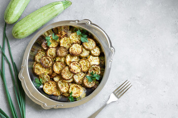 Fried zucchini with parsley in plate on rustic background, vegetarian food