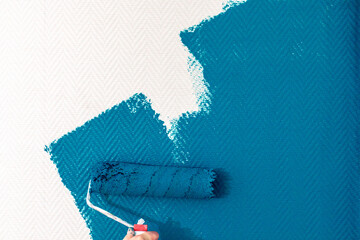 hand painting wall with paint roller. Painting apartment, renovating with color paint- Image