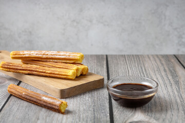 traditional Spanish pastries - Churros and chocolate sauce on a wooden background