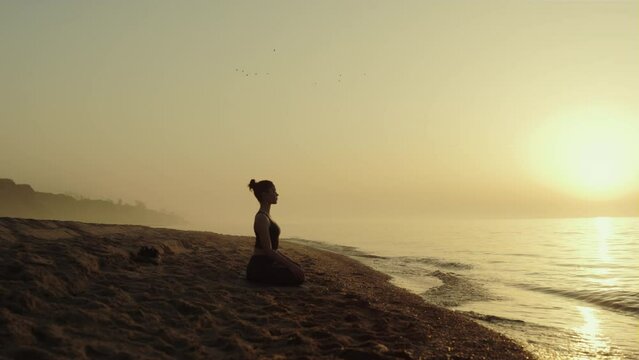 Yoga woman practicing meditation on sandy beach.Lady relaxing on nature.