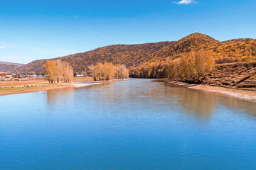 Naklejka premium Scenic view of wide river and small tranquil hills and mountains covered with autumn forest